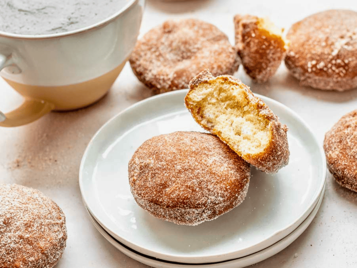 two circle sugar dough treats on a white plate with one bitten in half