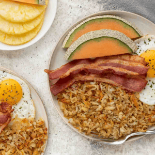 hash browns, egg bacon and fruit on plates