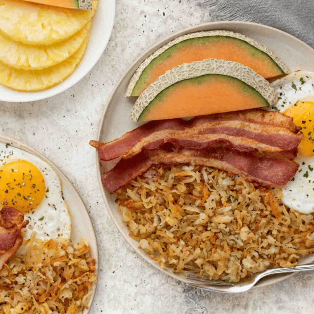 hash browns, egg bacon and fruit on plates