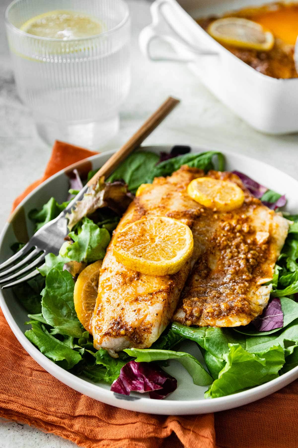 fish on top of salad on a plate 