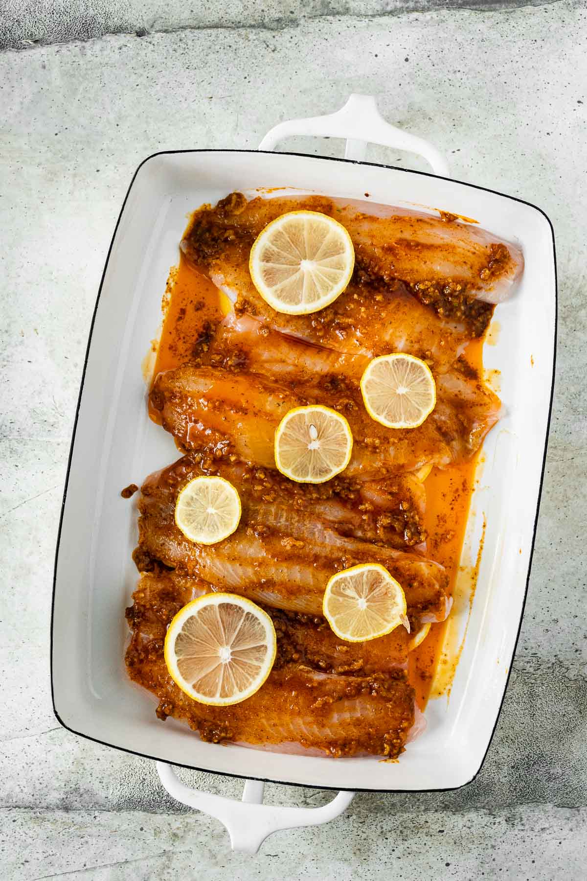 lemons topped on fish in baking dish 
