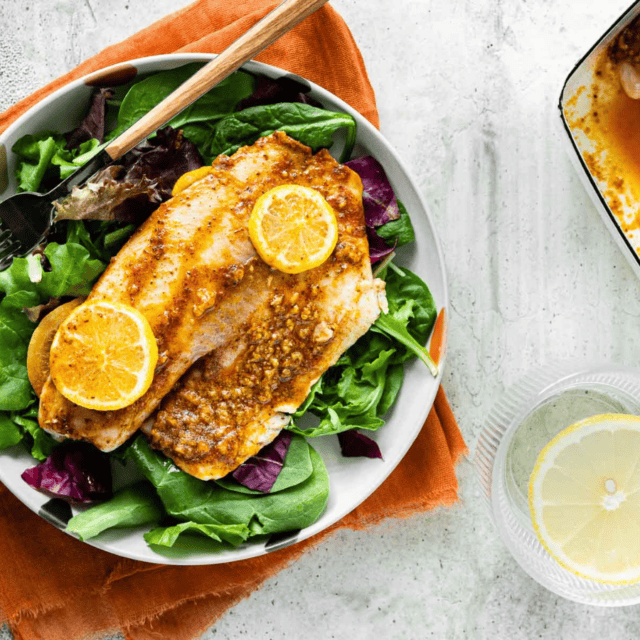 tilapia on top of lettuce on a plate with a fork