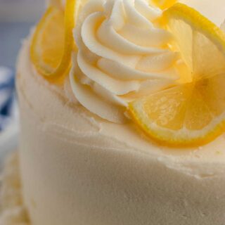 Lemon Cream Cheese Frosting close up of frosted lemon cake with frosting swirl on top and lemon wheels on mound, 1x1