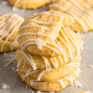 Citrus cookies with icing drizzled on top stacked on top of each other with a bite taken from the top