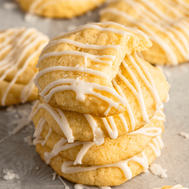Citrus cookies with icing drizzled on top stacked on top of each other with a bite taken from the top