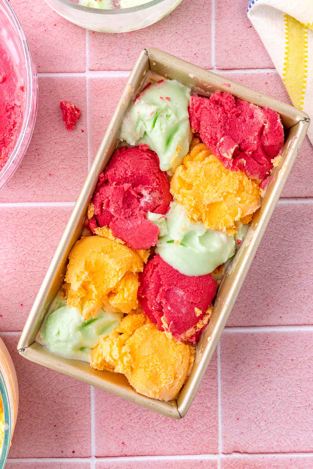 scoops of raspberry, orange, and lime sherbets alternating in a loaf pan
