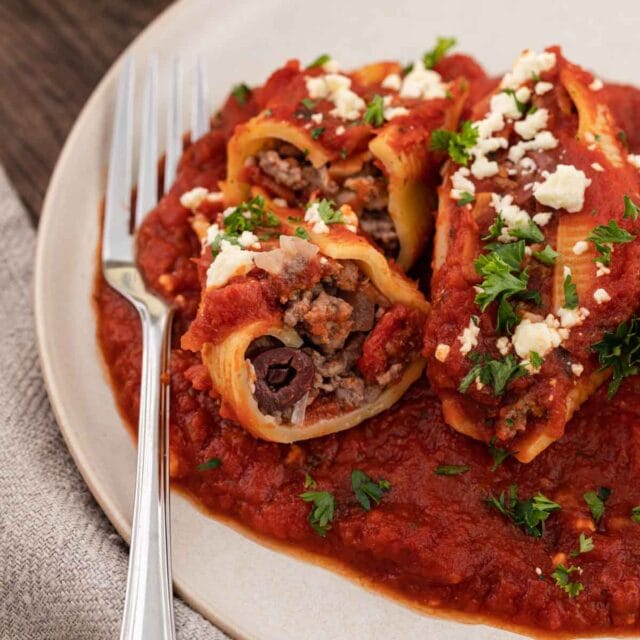 3 stuffed shells on a plate with a fork