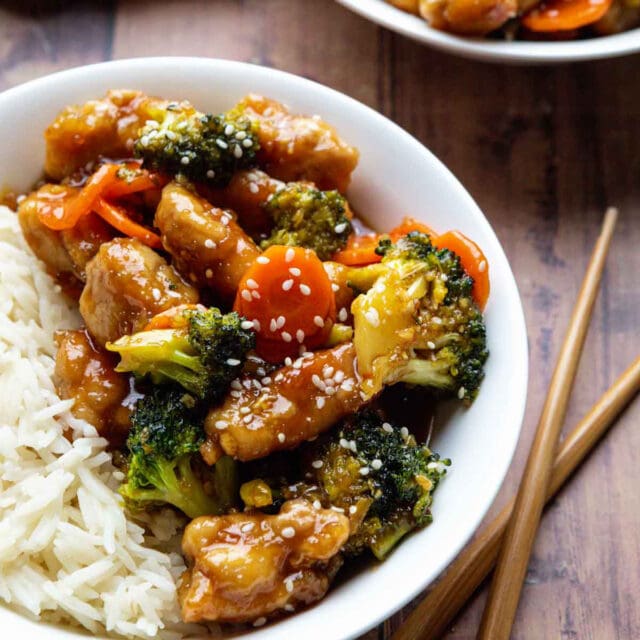 General Tso's Chicken Stir Fry plated on rice with chopsticks off to right side