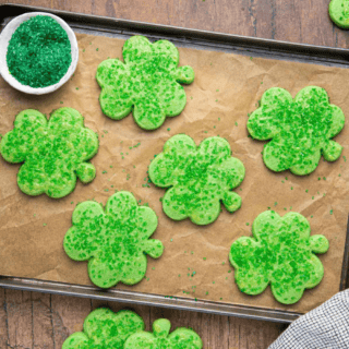 finished cookies on a cookie sheet with green sugar next to them