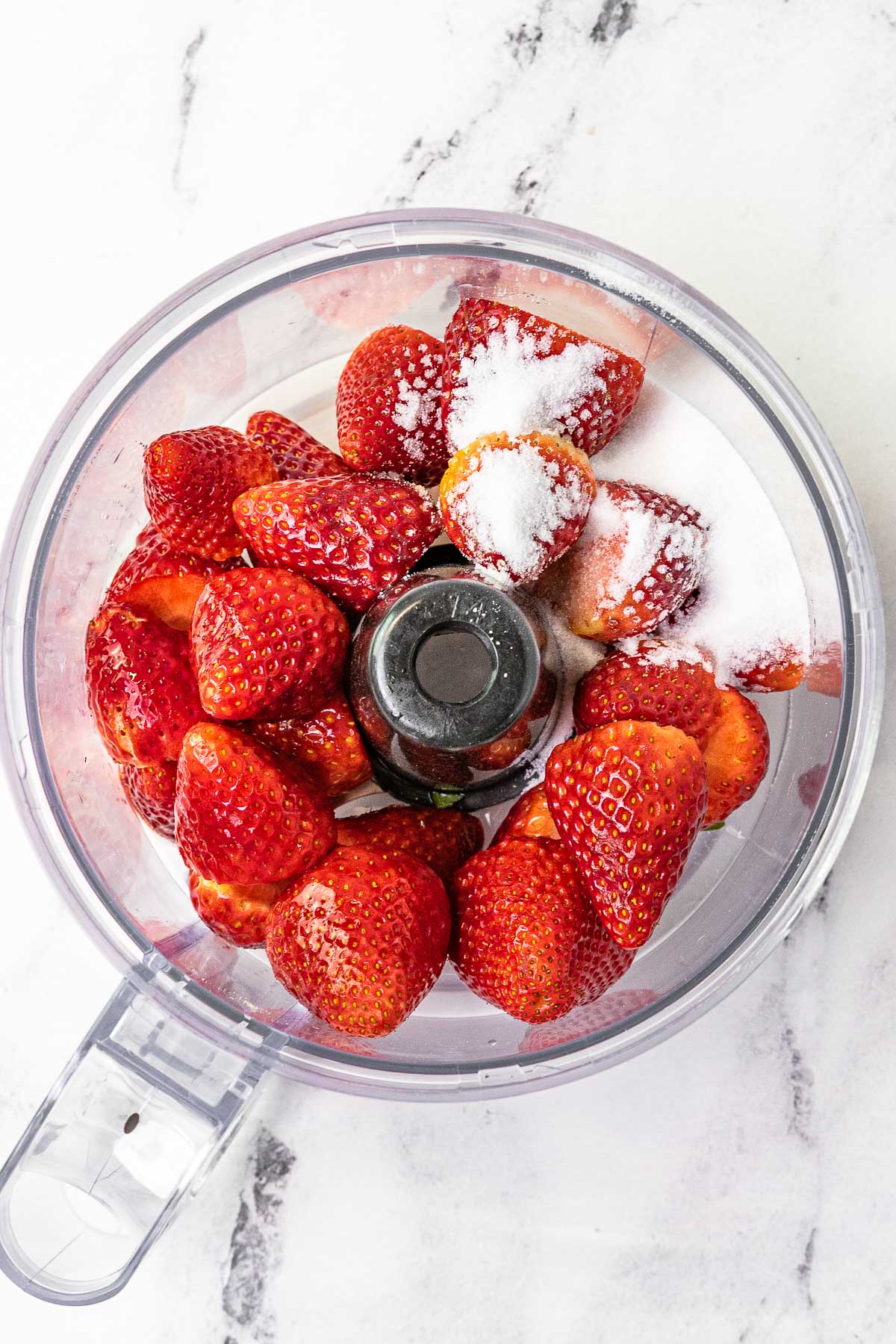 Strawberries and sugar in a food processor