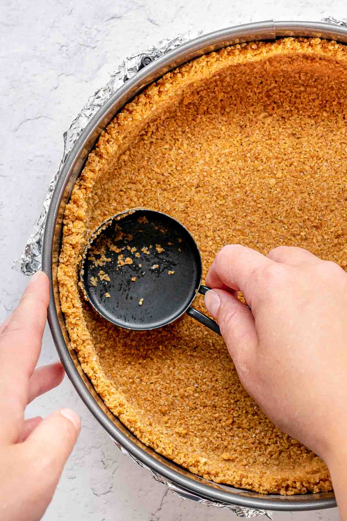 Coconut Cheesecake crust being pressed into baking dish