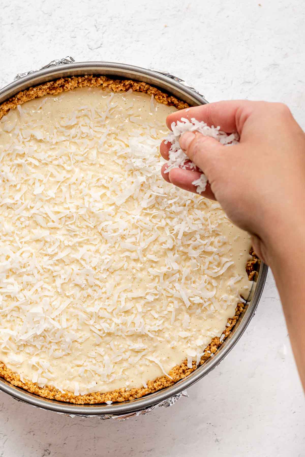 Coconut Cheesecake being topped with coconut