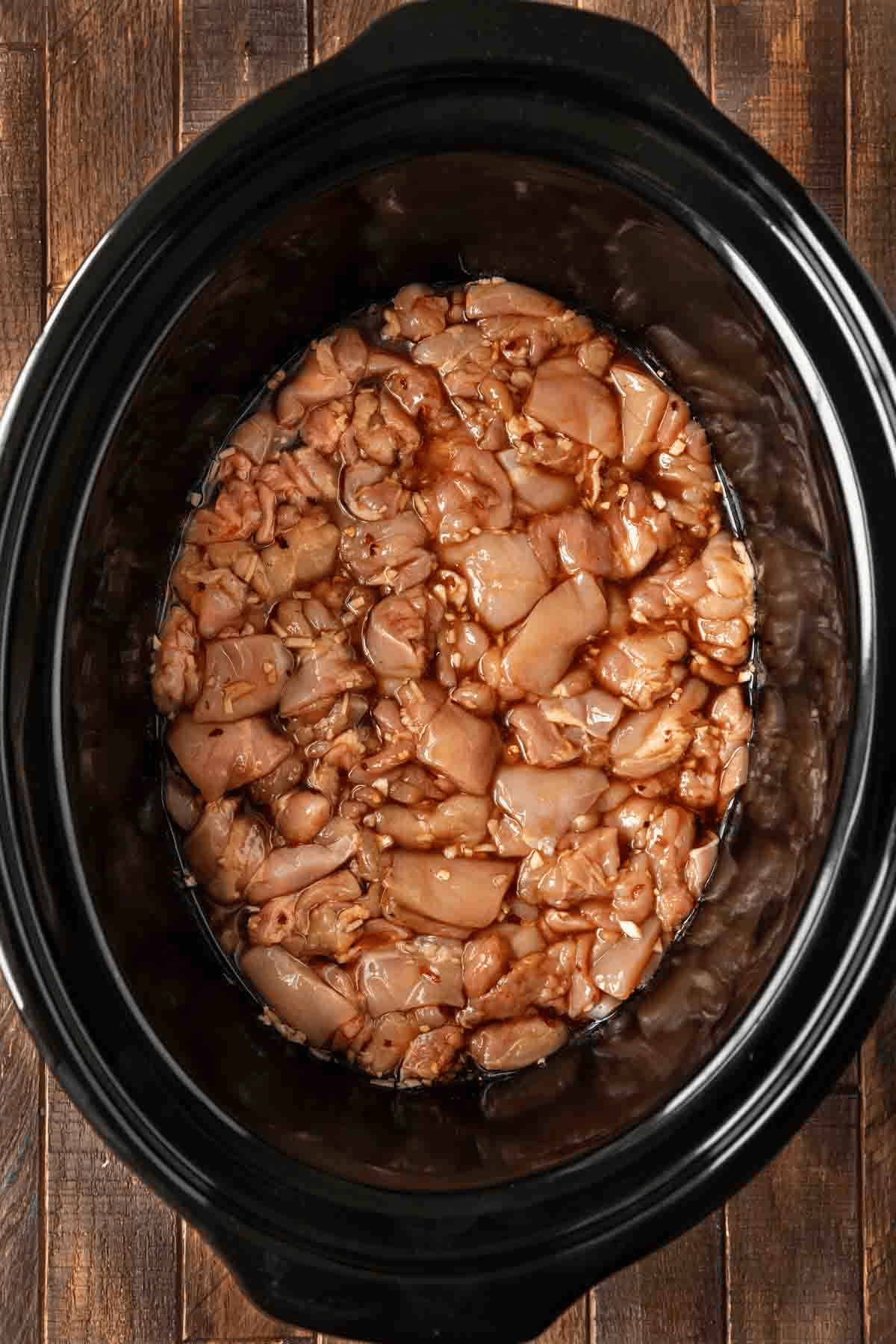 Raw chicken in sauce in a crockpot