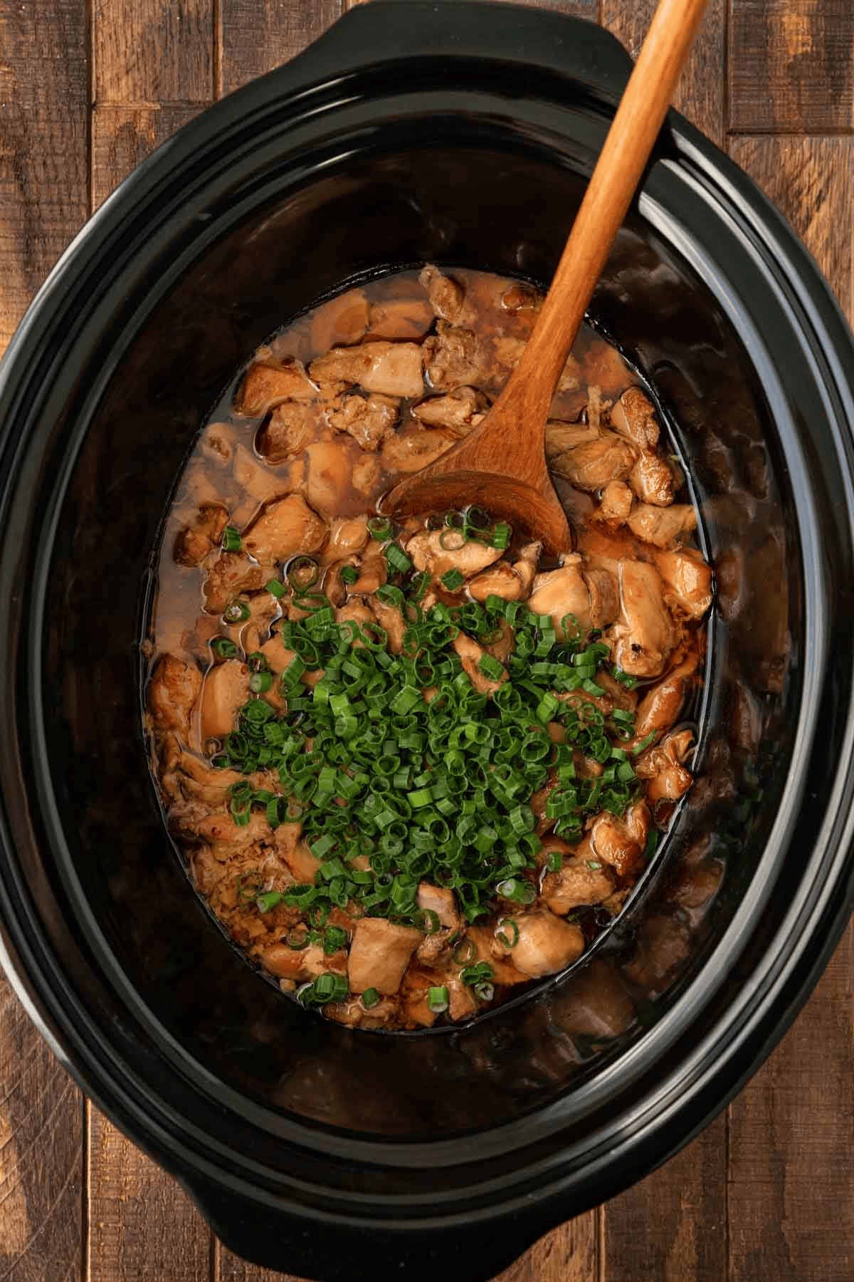 Chicken in a slow cooker topped with green onions