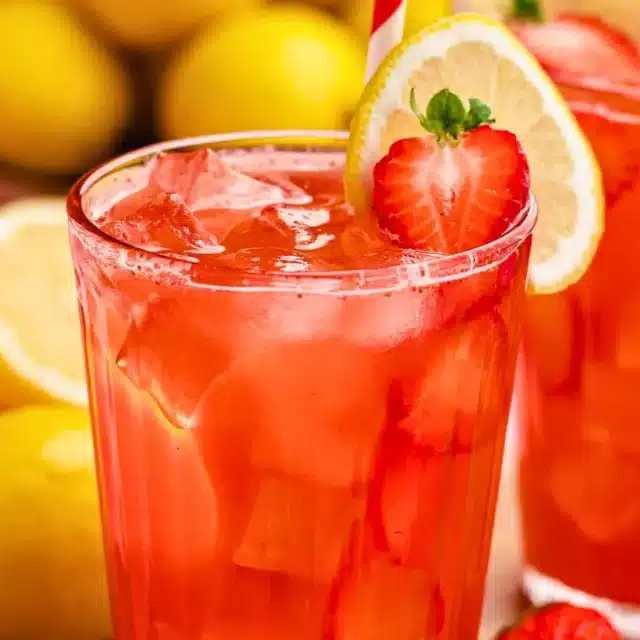 Red drink in glass with strawberries and lemons