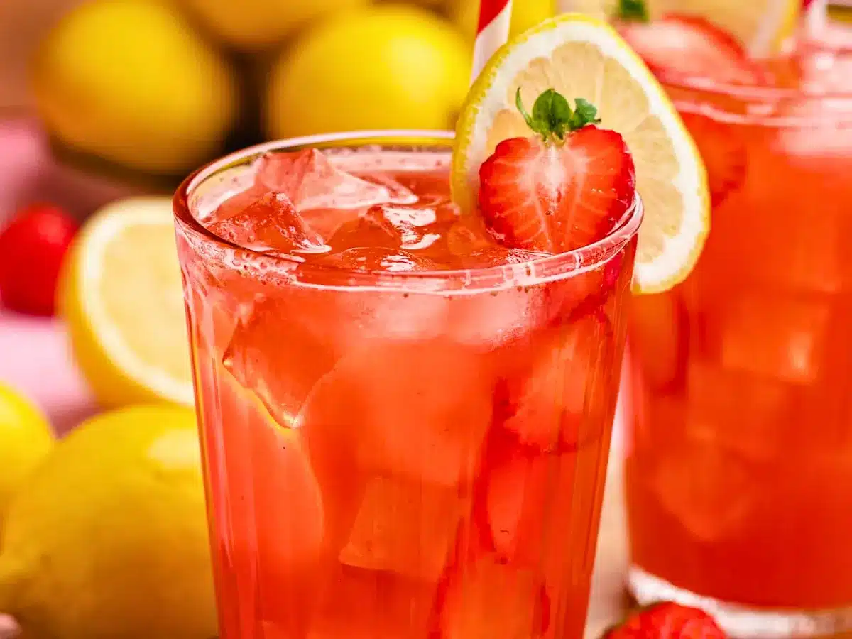 Red drink in glass with strawberries and lemons