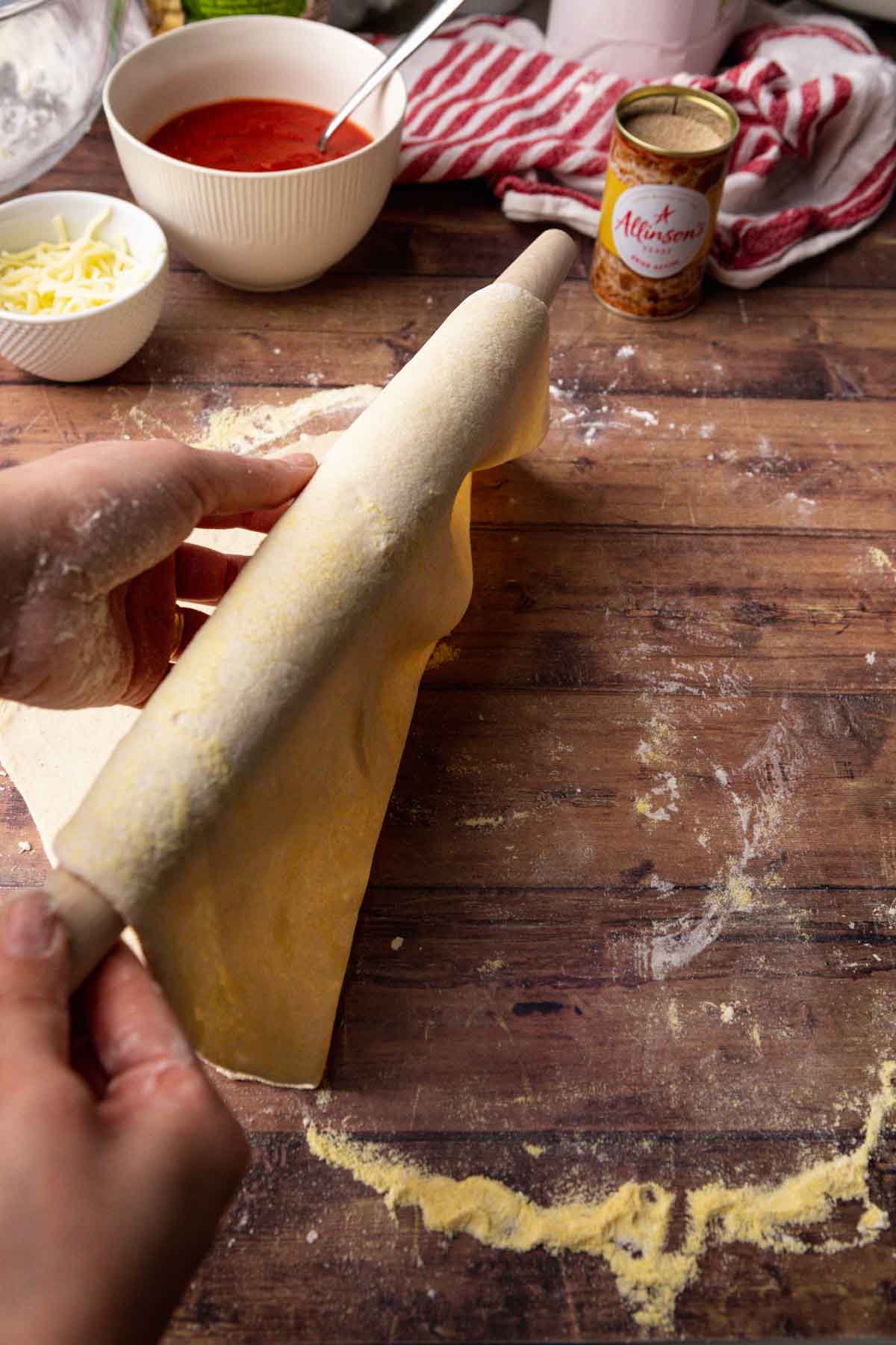Thin Crust Pepperoni Pizza picking up rolled out dough with rolling pin
