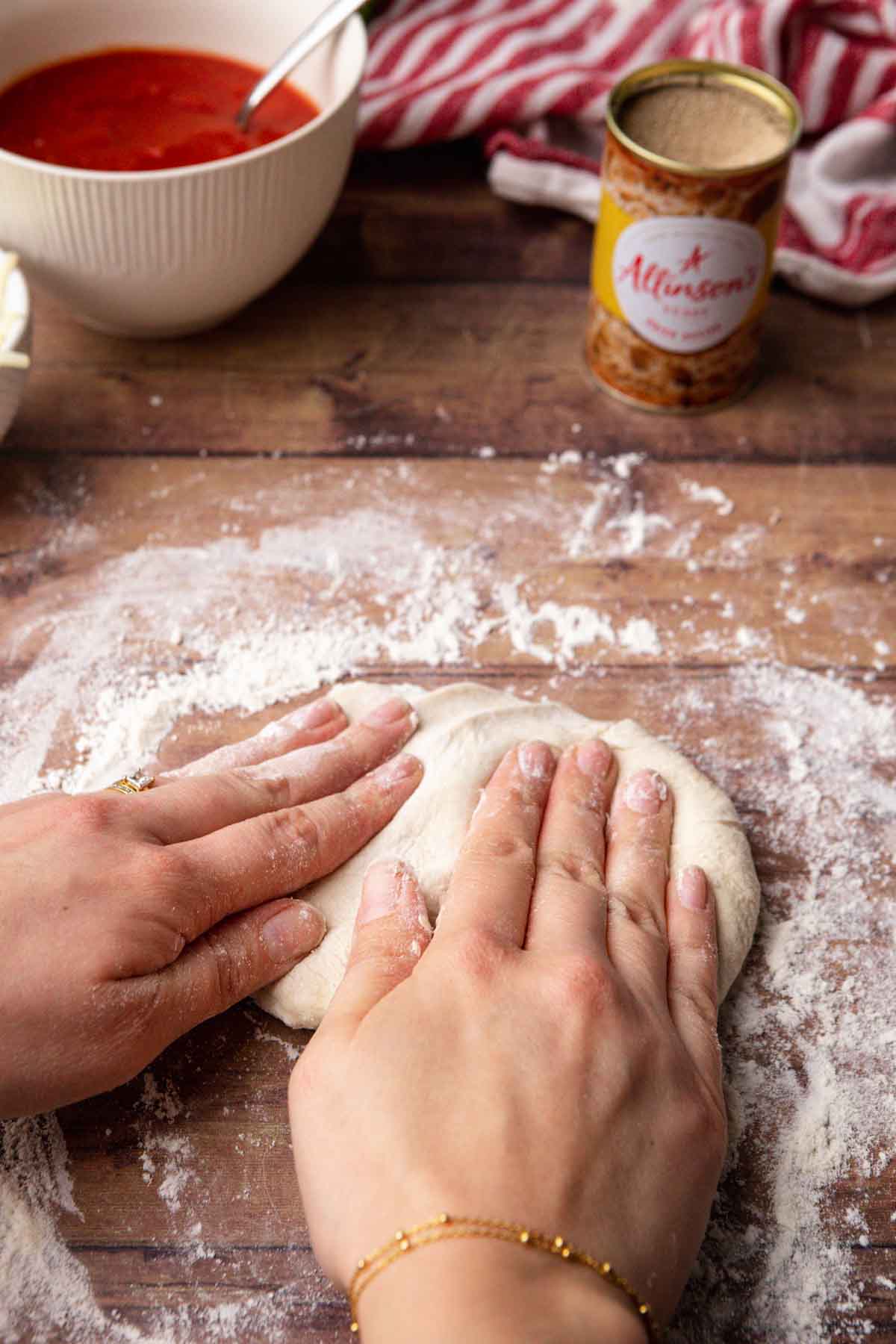 Thin Crust Pepperoni Pizza kneading pizza dough on wooden counter