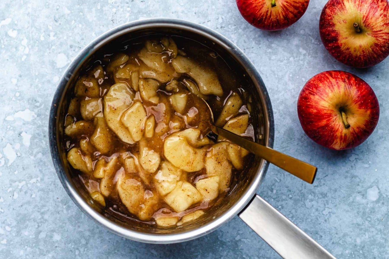 Apple Turnovers cooked apple slices with spices and reduced sauce, whole apples around pan