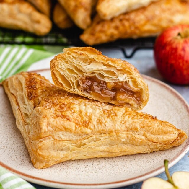 Apple Turnovers two baked turnovers on small plate, top turnover cut to see filling 1x1
