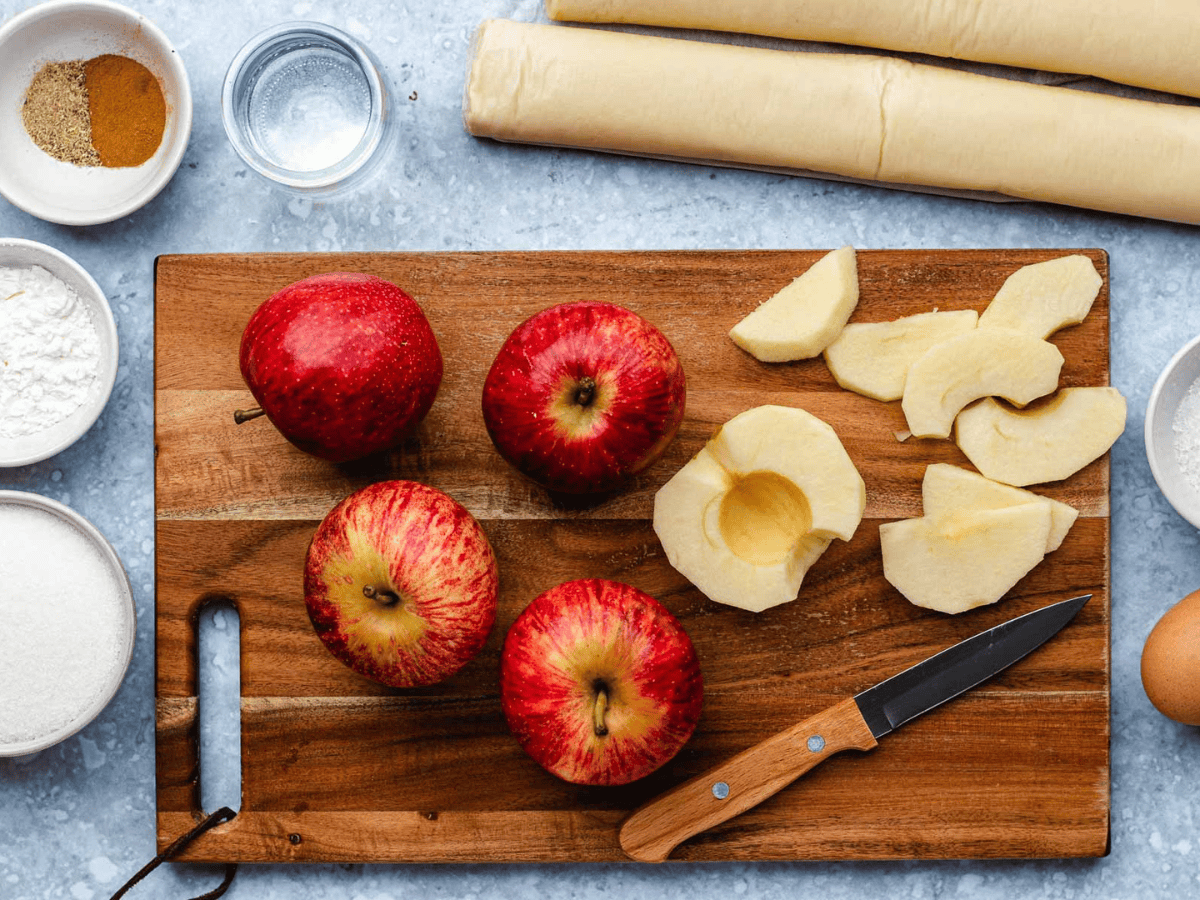 red apples on a cutting board with some cut into slices