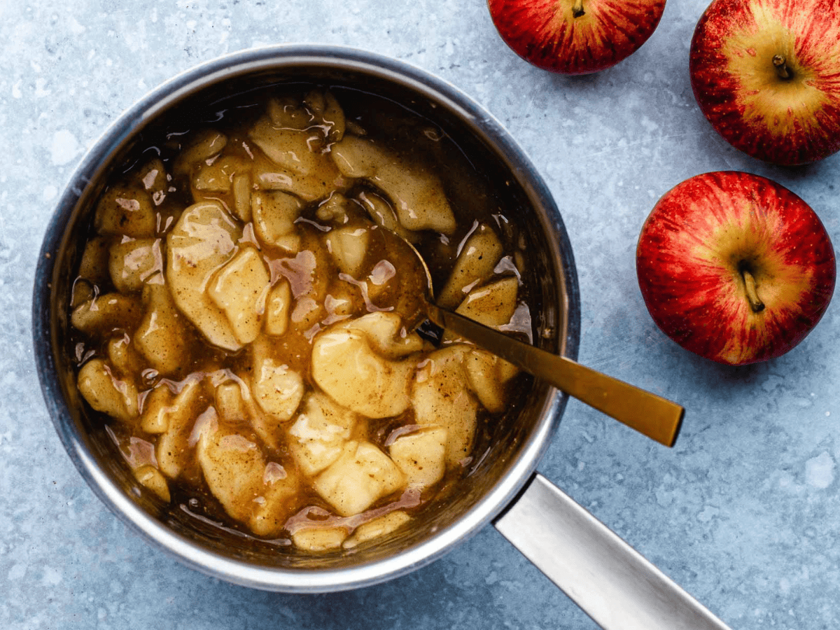 sliced apples in spices in a pot with a spoon