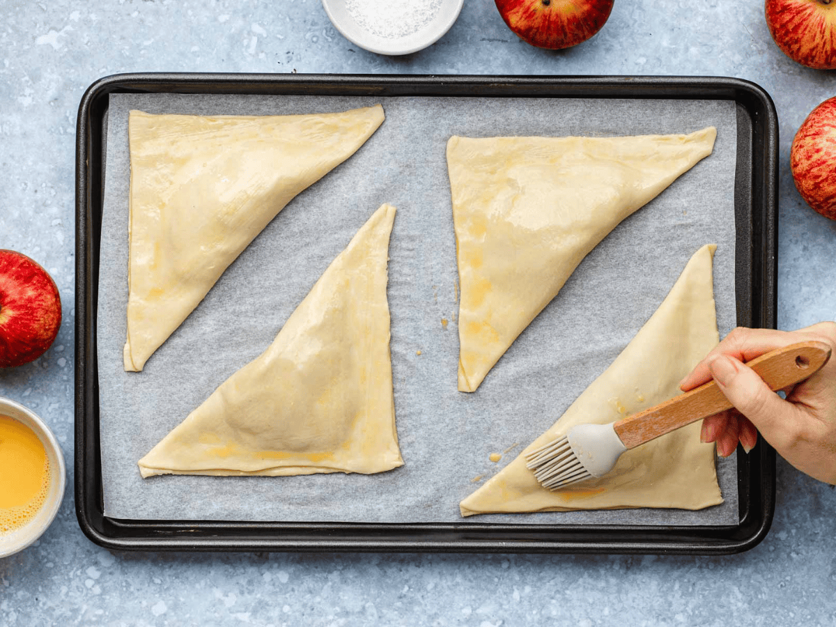 raw dough triangles on parchment paper and baking sheet