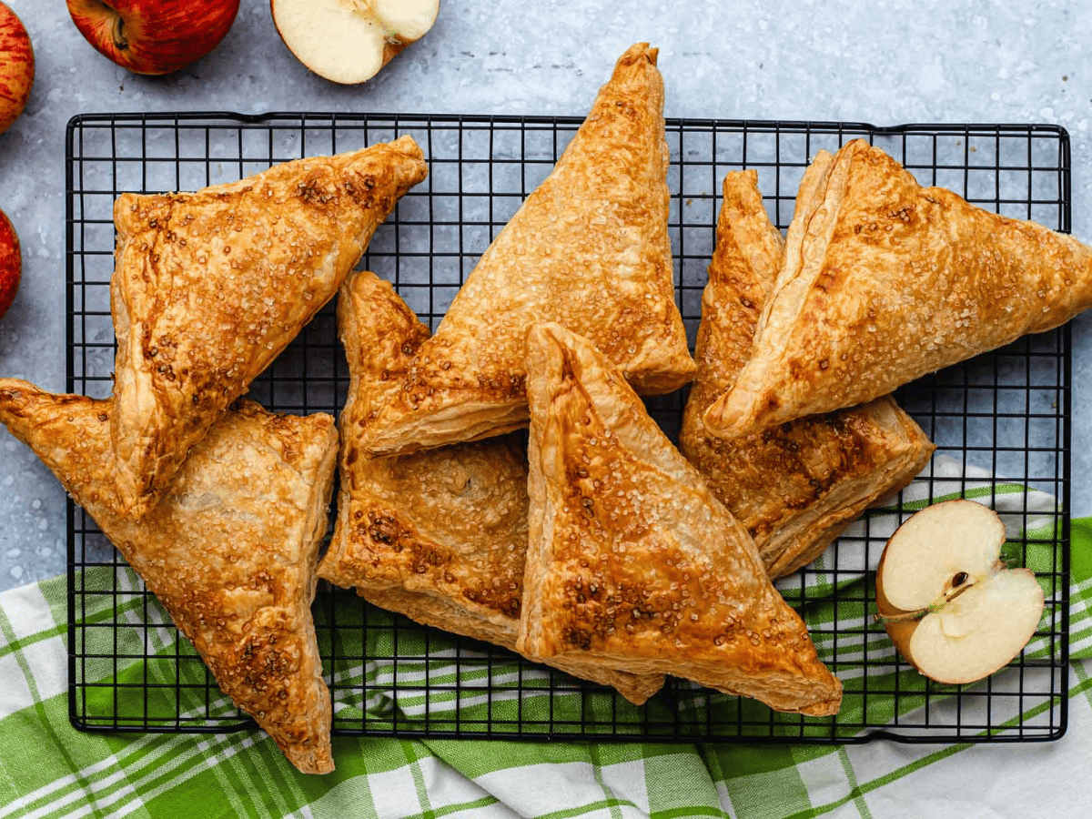 baked triangle pastries on a cooling rack with half an apple