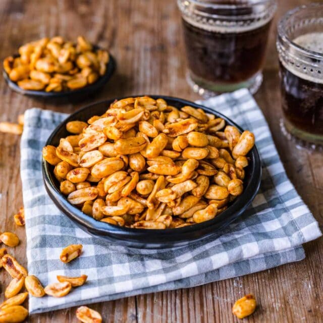 Planters Heat Peanuts piled on a plate on napkin, two glasses of cola next to napkin on right