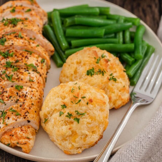 Garlic Cheddar Biscuits two biscuits plated with sliced seasoned chicken breasts and green beans, 1x1