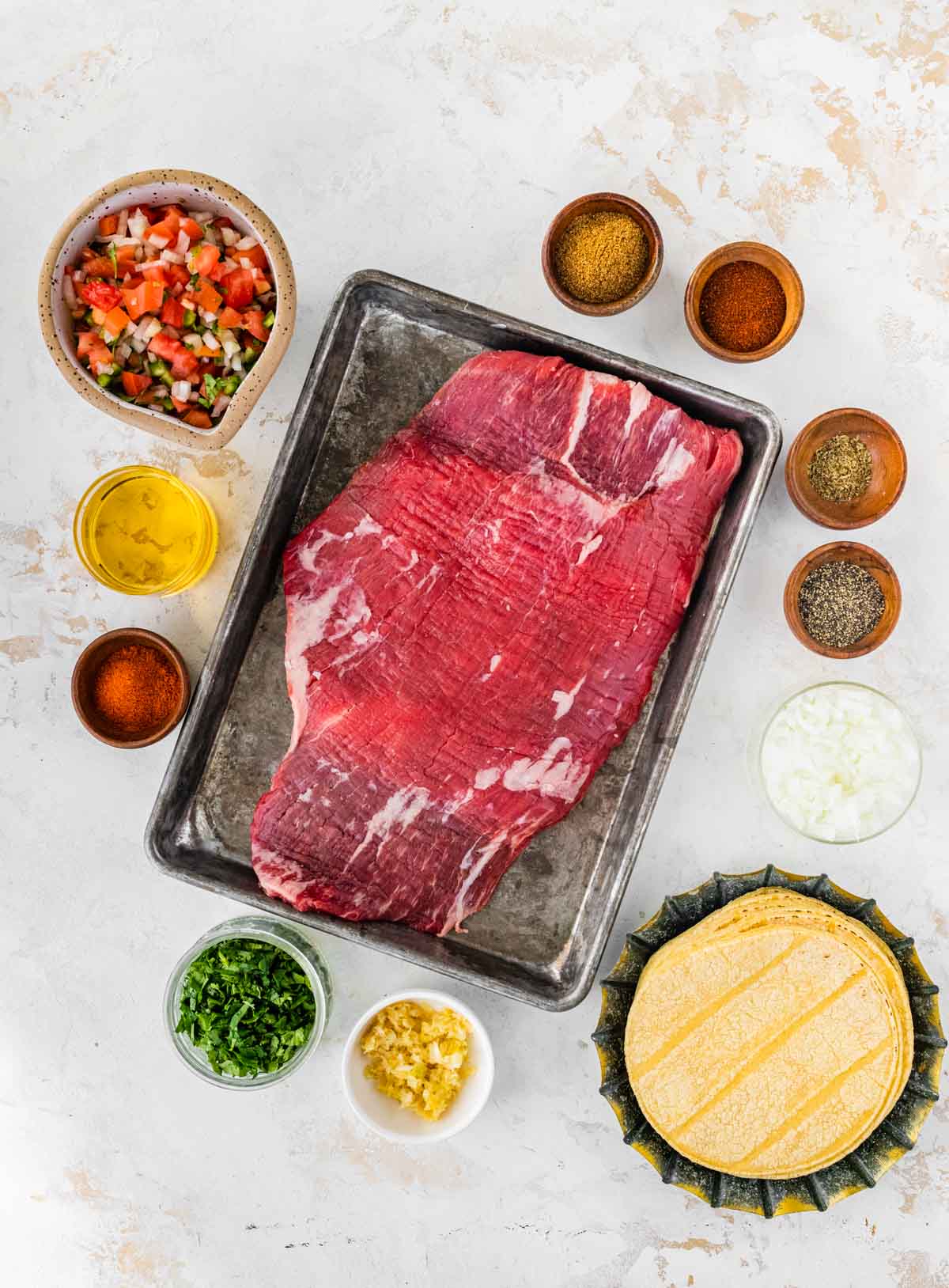 Steak Tacos ingredients in separate prep bowls and steak on baking pan