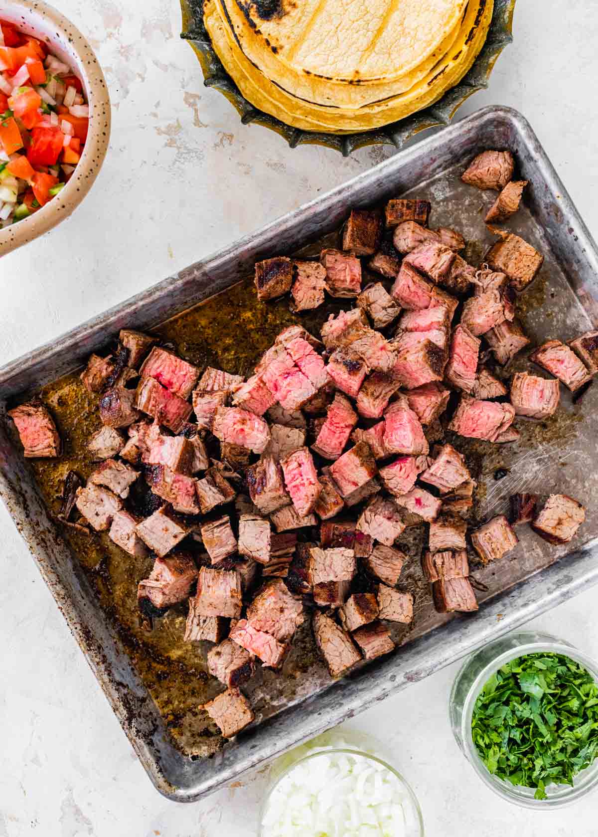 Steak Tacos diced steak in baking pan, toppings in small bowls
