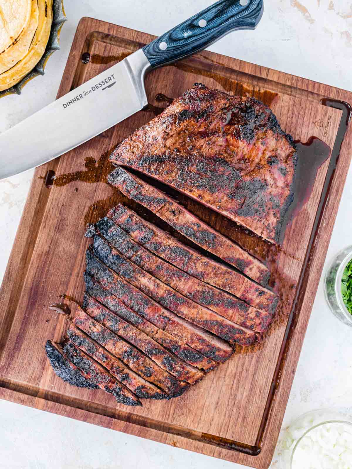 Steak Tacos cooked steak on wooden board with knife, half sliced in strips and half uncut