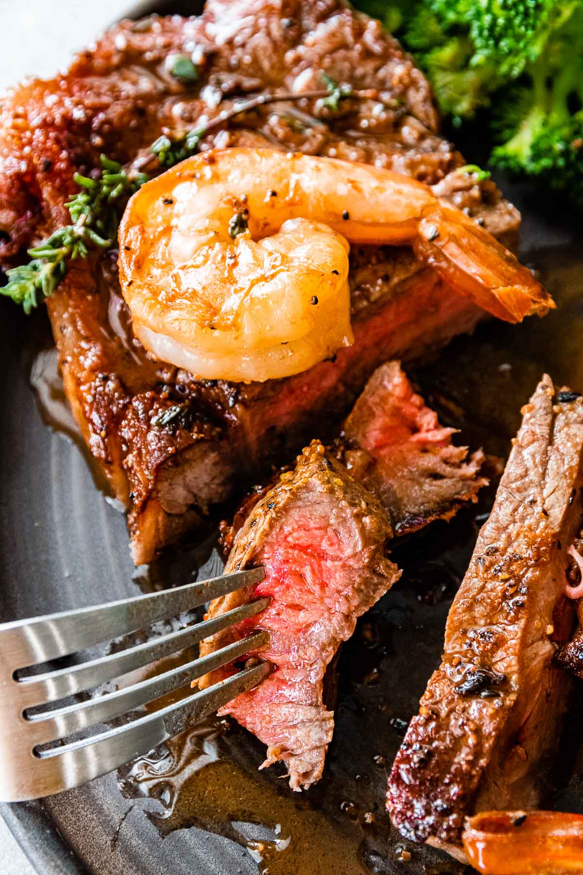 fork with cut of medium rare steak and a shrimp