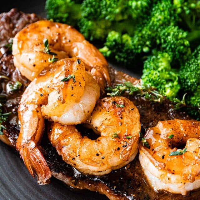 new york steak topped with shrimp and a side of broccoli
