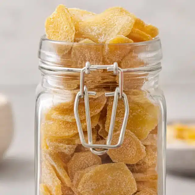 Glass jar filled with sugar coated ginger slices.