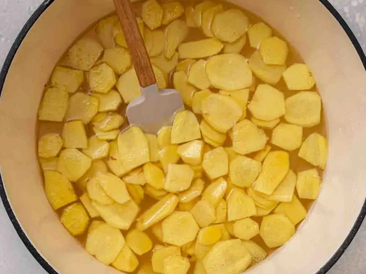 Ginger slices simmering in pot of water and sugar.