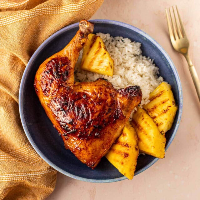 Hawaiian BBQ Chicken plated chicken leg quarters with pineapple wedges and white rice. 1x1