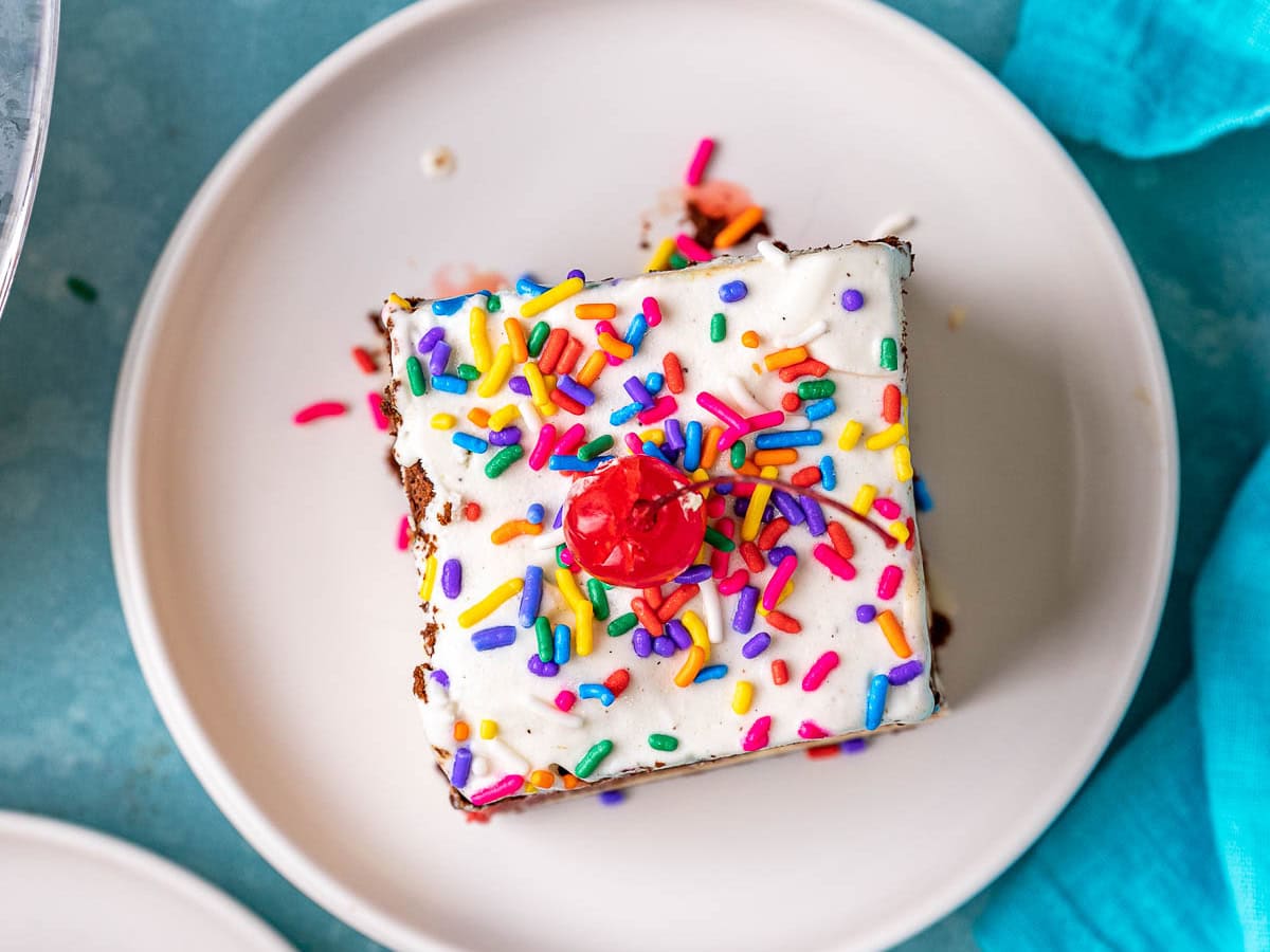 Ice Cream Sandwich Cake top down view of slice on plate topped with maraschino cherry.