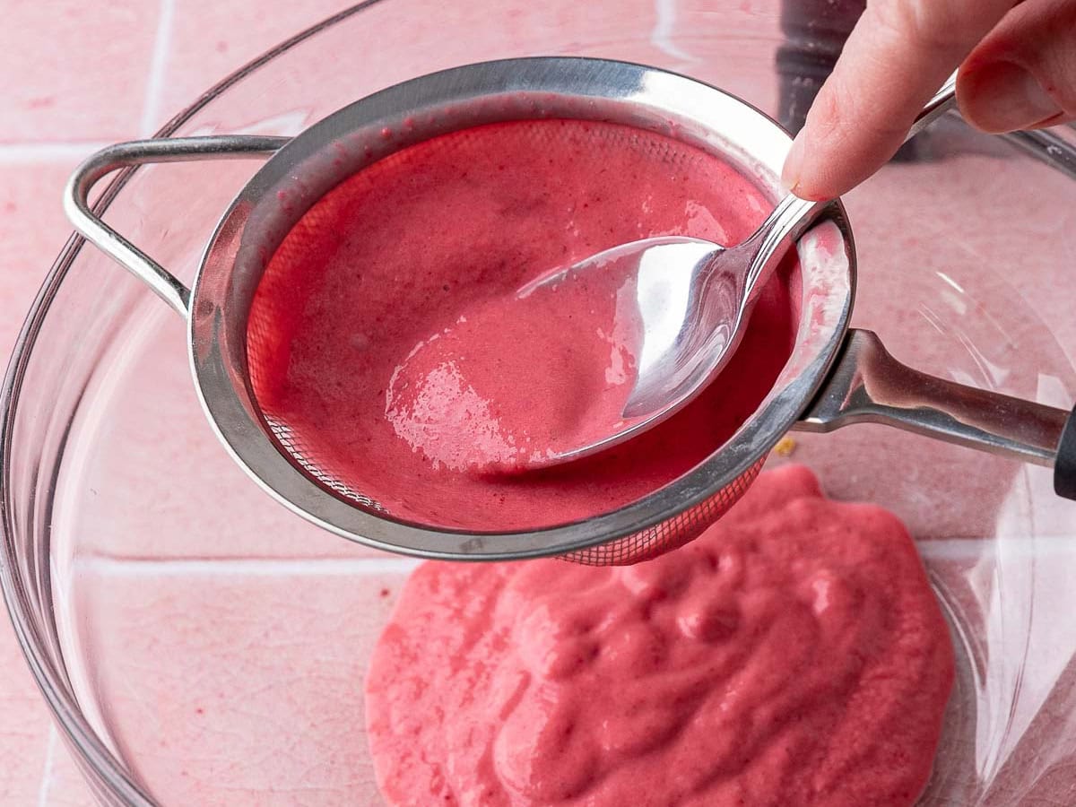 Raspberry Sherbet pressing raspberry mixture through sieve to remove seeds.