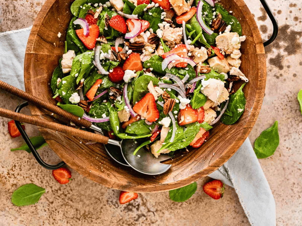 green veggies, berries, chicken, onions, and nuts mixed with dressing