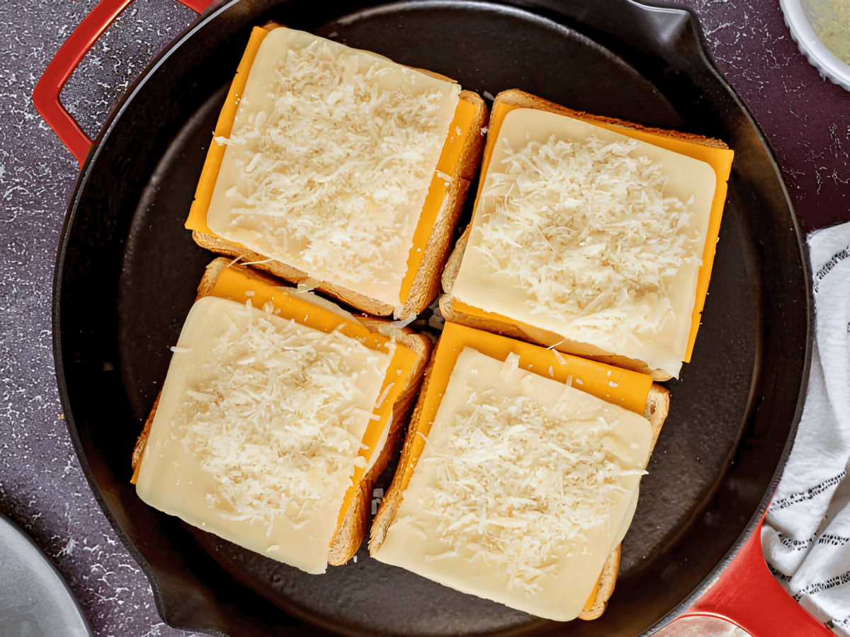 four slices of bread on a skillet with cold cheese on top of each