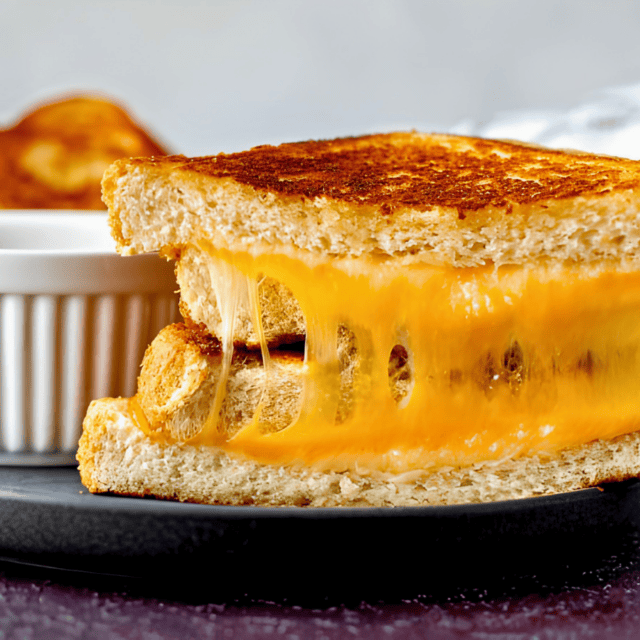 sandwich on a plate with a bowl of coup next to it