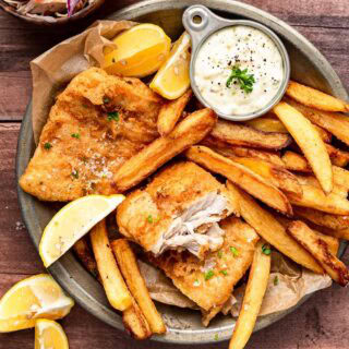 Plated fried fish and fries with tartar sauce and lemon