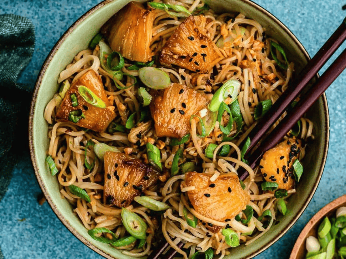 bowl of noodles with pineapple on top and chopsticks in bowl
