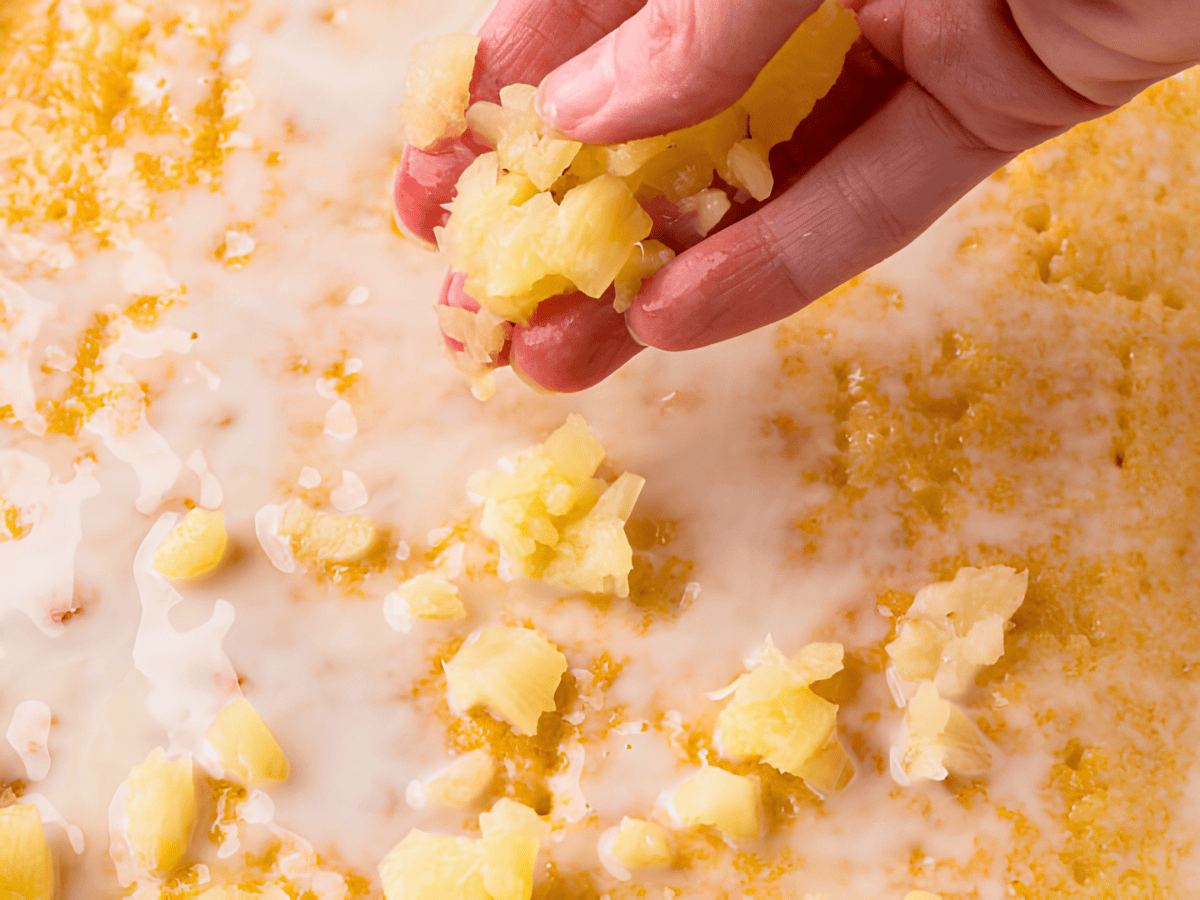 handful of crushed pineapples spreading it on top of cake