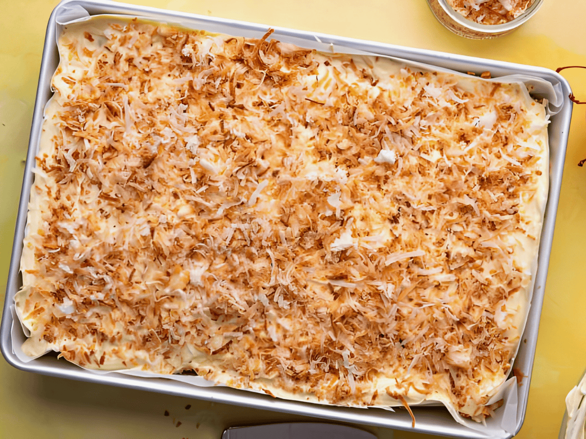 shredded coconut on top of a bed of frosting in cake pan