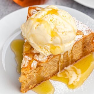 slice of moist dessert with sticky nectar and a scoop of ice cream on top on a plate