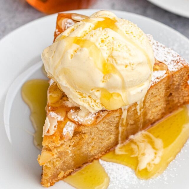 slice of moist dessert with sticky nectar and a scoop of ice cream on top on a plate