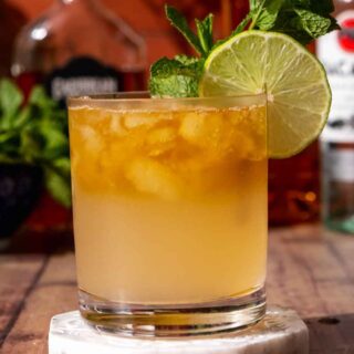 Cocktail in rocks glass with mint and lime garnish